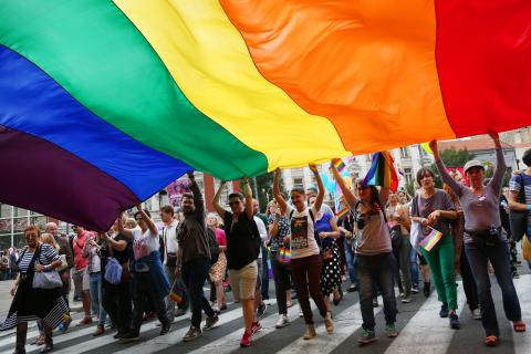 Een groep mensen op straat met de regenboogvlag