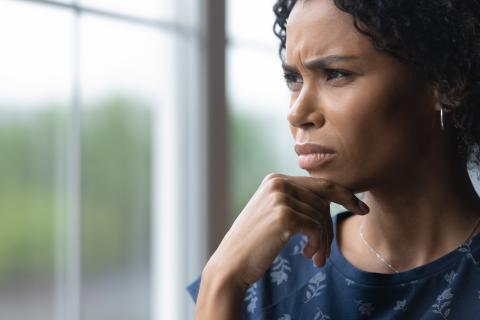 Vrouw kijkt bedrukt uit raam