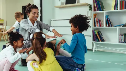 Groepje kinderen dat samen speelt met begeleider